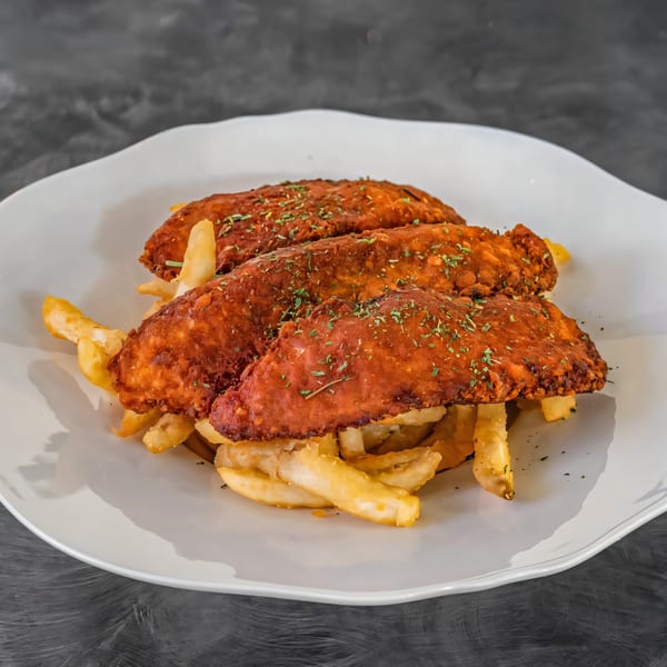 Three crispy, red-orange chicken tenders topped with herbs, served over a bed of golden french fries.